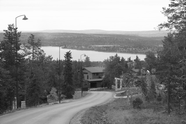 Hilly road, houses and a lake in Kuusamo